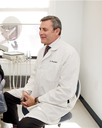 Dr. Jeffry Nirenstein in his white coat, talking with a patient in the exam room